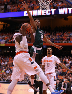 Christmas holds the ball as Loyola guard Colton Bishop leaves his feet and SU forward Michael Gbinije looks on.