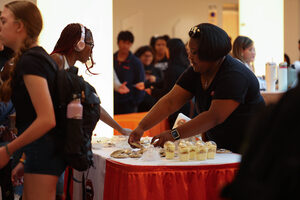 Kayla Johnson, owner of Worth the Kavity, hands pastries to students at Syracuse University’s Dessert Crawl. Her business specializes in cookies, chocolate-covered strawberries and other sweet treats. 