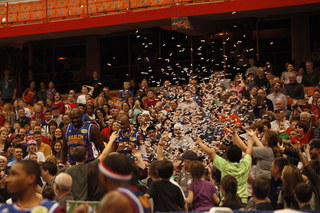 Big Easy and Scooter take their act to the stands, throwing confetti into the air as members of the crowd look on and laugh. 