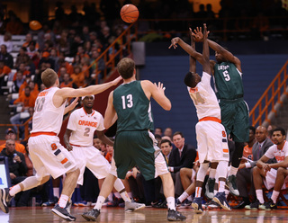 Loyola guard Eric Laster fires a shot contested by Syracuse point guard Kaleb Joseph.