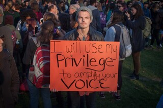 Daniel Roezter, a senior international relations major at Syracuse University, holds a sign reading 