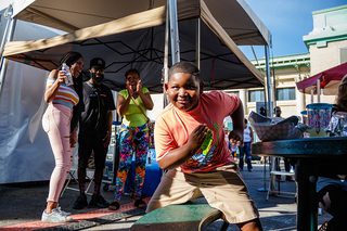 Rayguwan Sparks dances along to the Cha Cha Slide from his seat as fairgoers Lourie White, Regis Holman and Madea Holman cheer from the side.