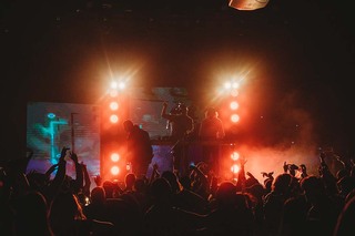 Fog and lights illuminate performers from behind as they take the stage. 